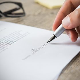 close up of a hand signing a document